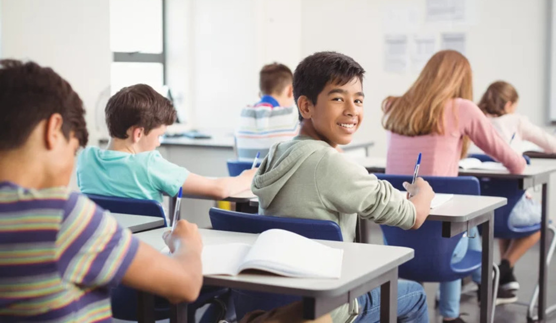 A group of students attentively sitting at desks in a classroom, engaged in learning activities.