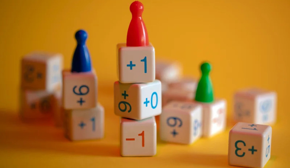 A close-up of a pile of wooden dice, each displaying various numbers on their faces.
