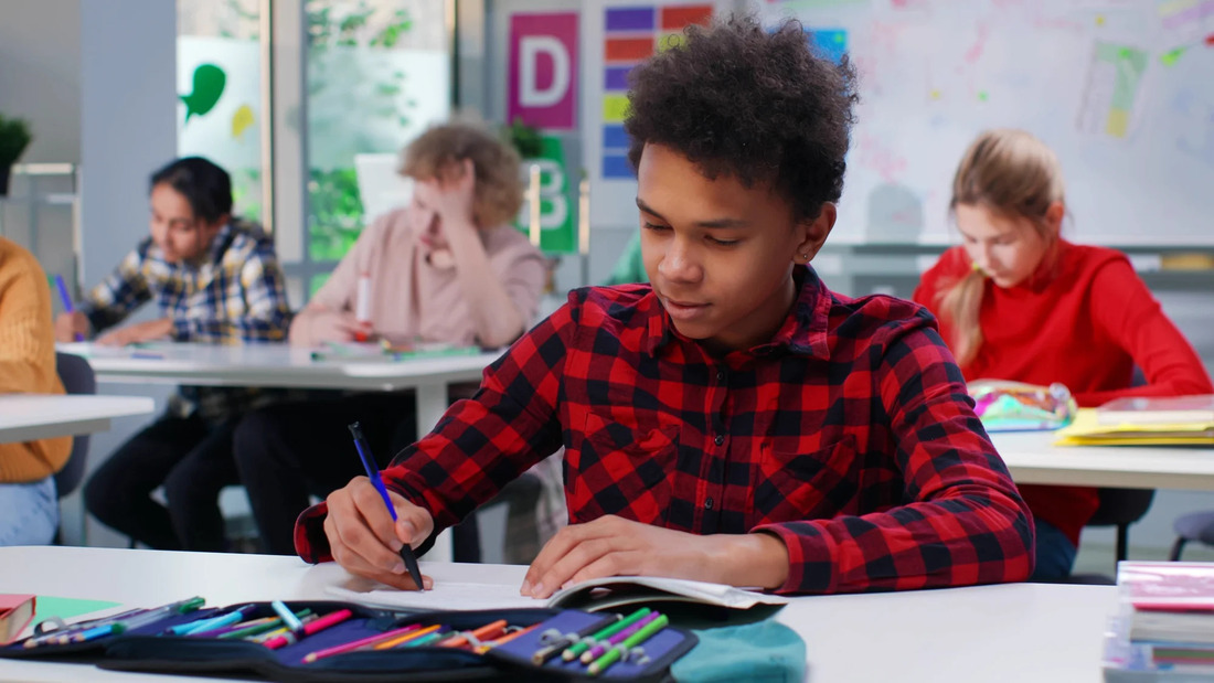 A group of students collaborates at a table, surrounded by pens and pencils, engaged in a study session.