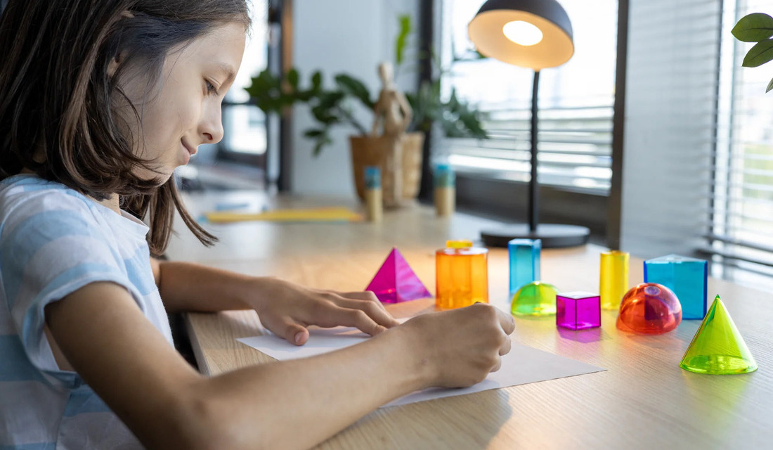 A girl sits at a table surrounded by various colorful plastic toys, engaged in play and exploration.