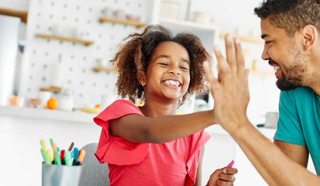 A man and a young girl joyfully exchanging high fives, showcasing a moment of connection and celebration.