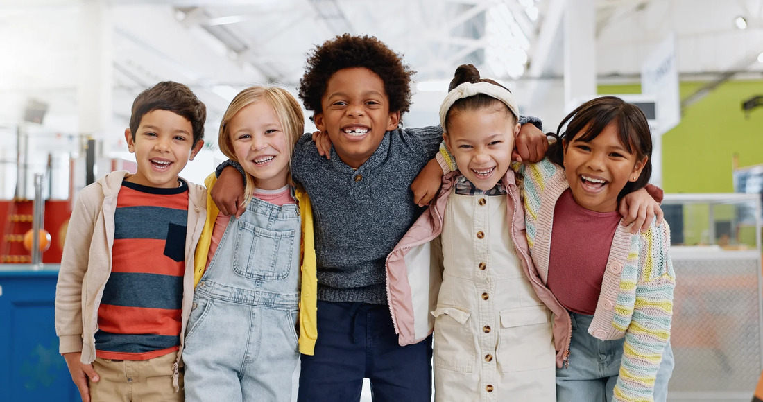 Several children stand together, all smiling brightly, capturing a moment of happiness and camaraderie.