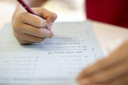 the hand of a student filling a math test