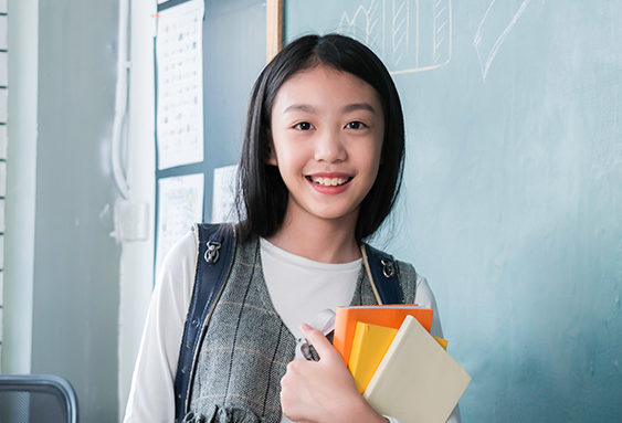 Teenage girl holding books and smiling in a pre-algebra tutoring class