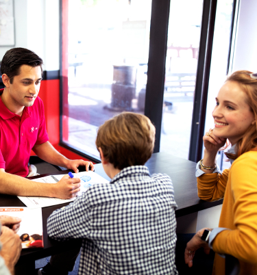 Math tutor explaining concepts to a student while parents smile and listen
