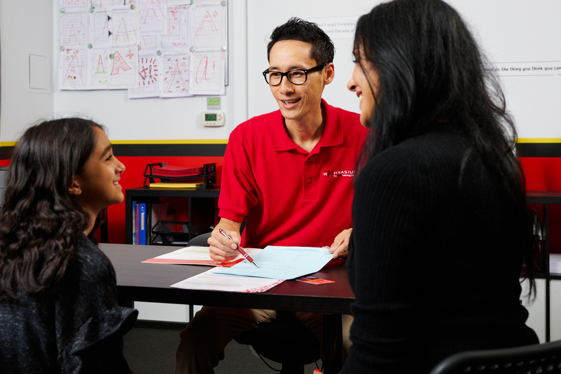 Mathnasium tutor discussing students progress with student and her mom.