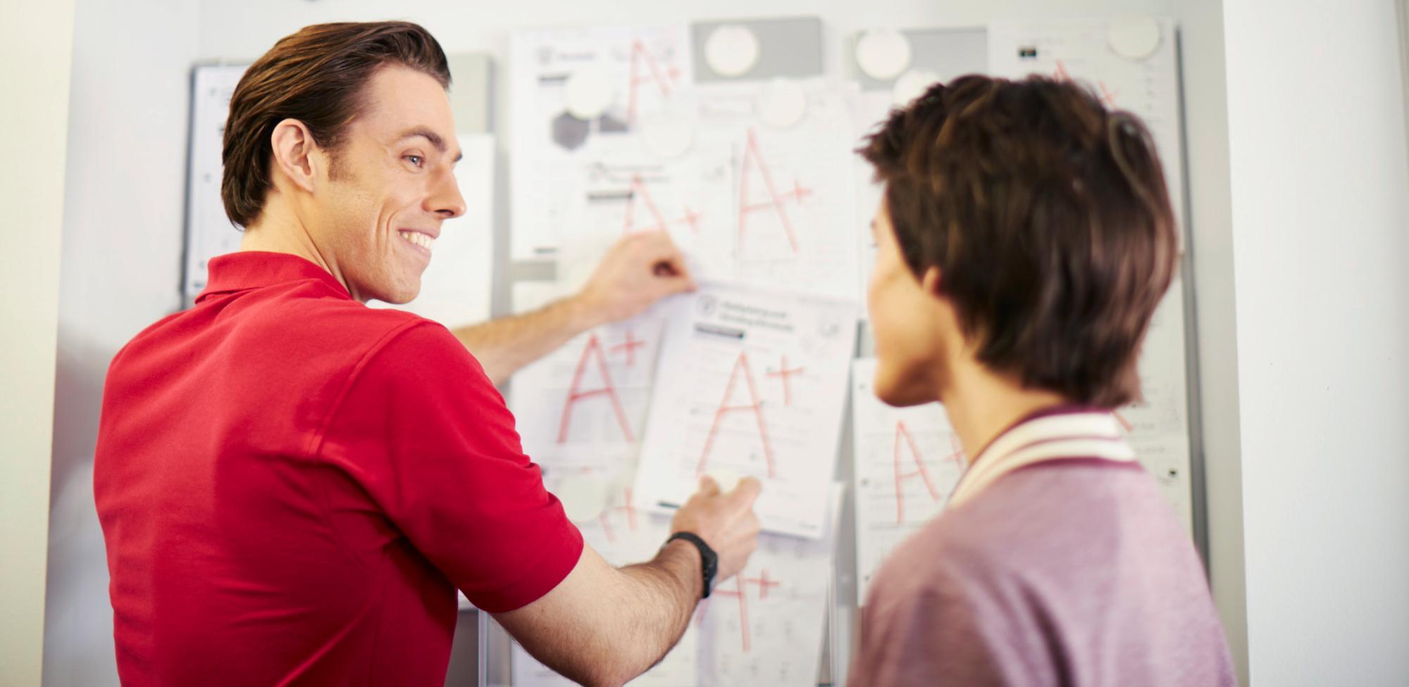 A male tutor and a female student collaborate at a whiteboard, discussing concepts and solutions together.