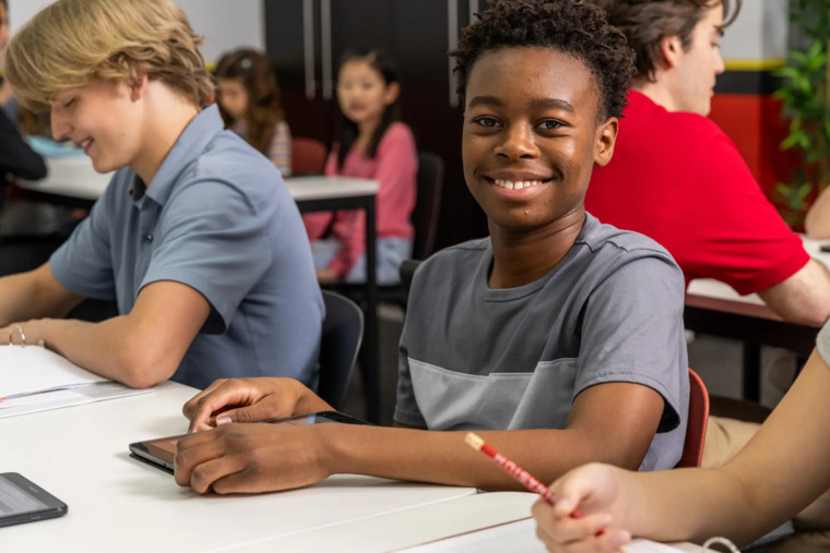 A group of students attentively sitting at desks in a classroom, engaged in learning activities.