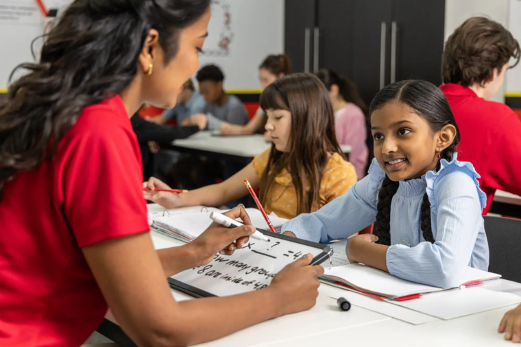A classroom scene featuring a teacher engaging with students during a lesson.