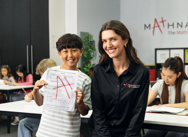 A woman and a boy stand side by side, showcasing a piece of paper with cheerful expressions.