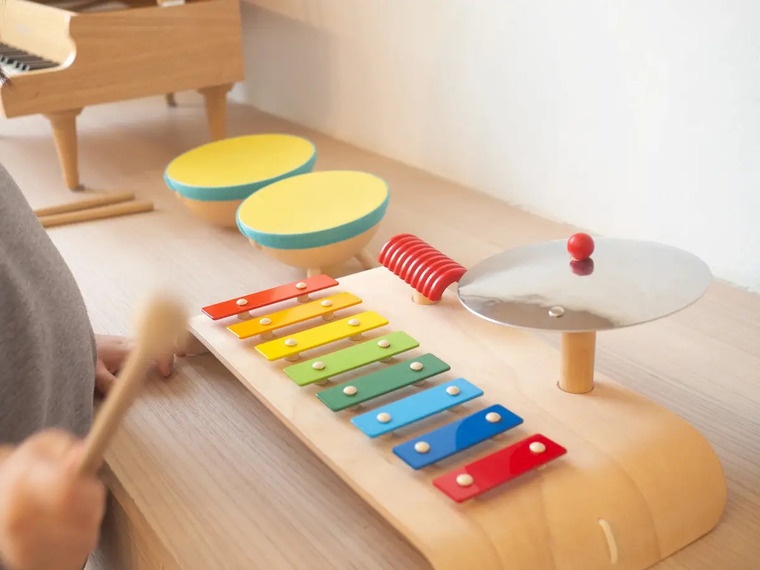 A child joyfully playing a wooden musical instrument, showcasing creativity and engagement in music.