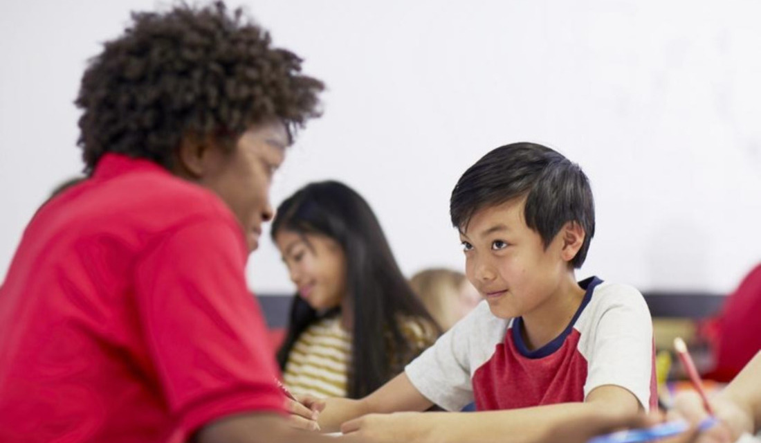 A group of children attentively sitting at desks in a bright classroom, engaged in learning activities.