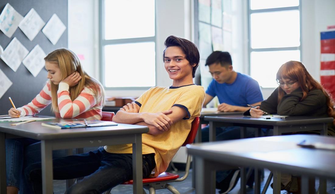 A classroom scene featuring students at desks, participating in lessons and collaborating on assignments.