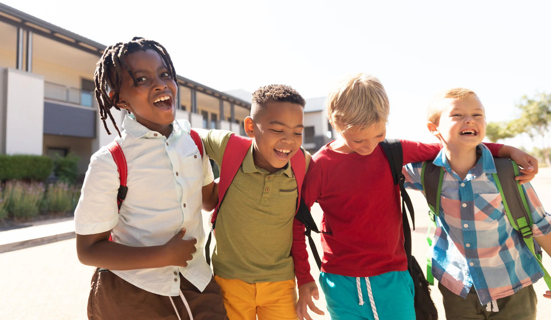 Four children stand together, smiling joyfully, showcasing a moment of friendship and happiness.