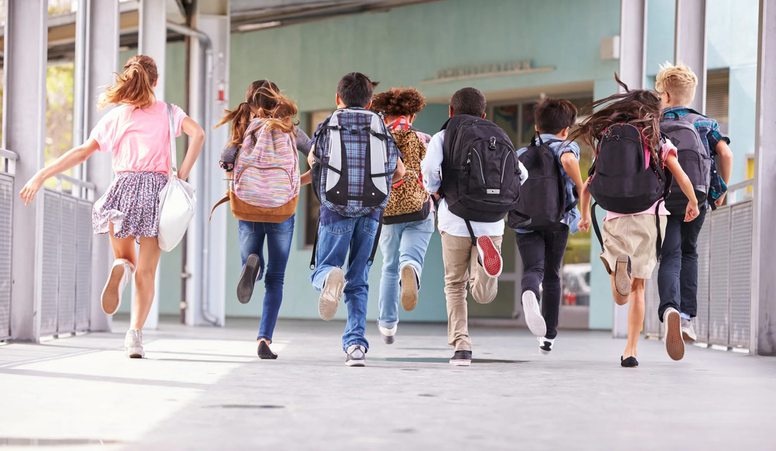 A group of young people energetically running down a brightly lit hallway.